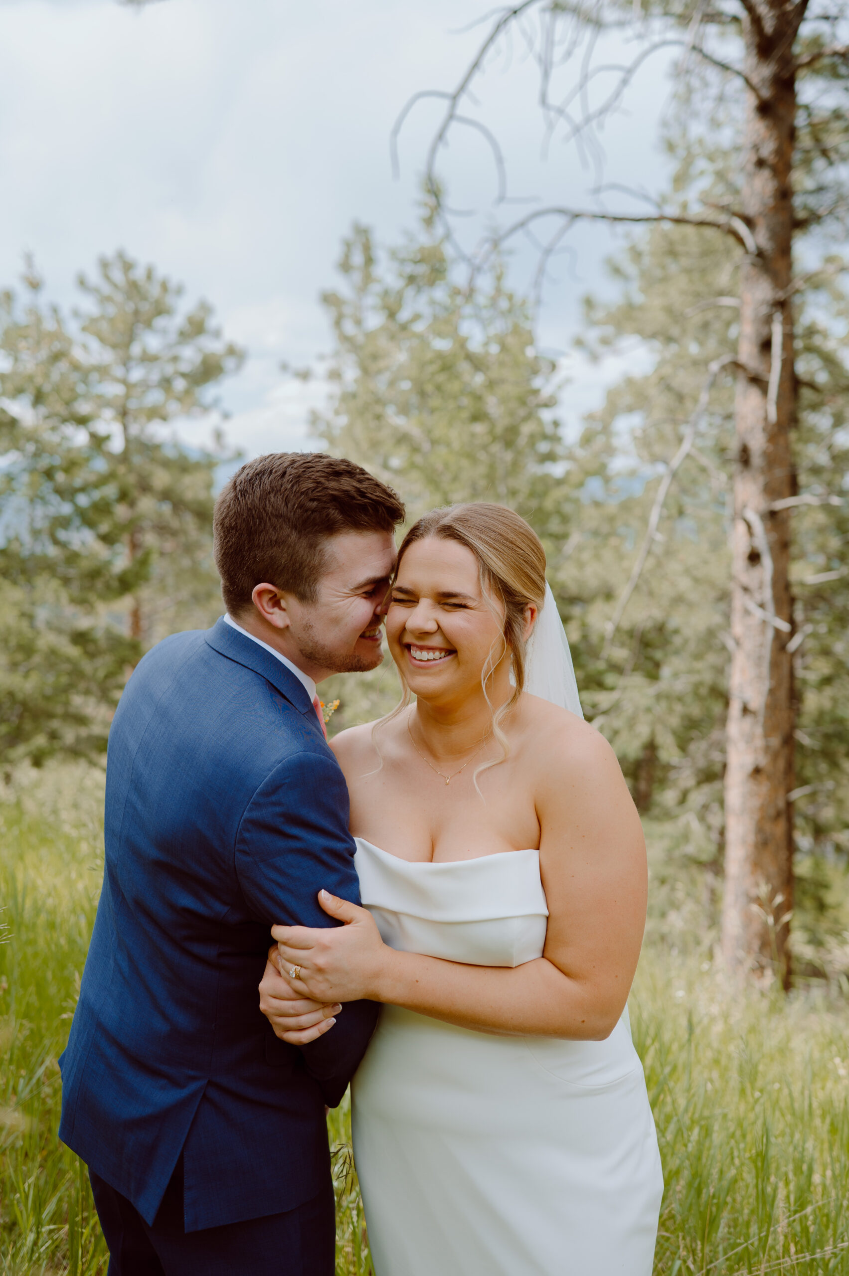 Bride and groom laugh together in mountain forest